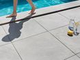Quelqu'un marche pieds nus sur la plage de piscine en grès cérame imitation ardoise Alpine Grey