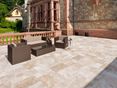 Dalle Medium, en travertin tambouriné. Une terrasse avec des meubles de jardin et un mur en pierre naturelle