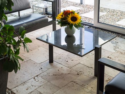 Le travertin Rustic au sol du jardin d'hiver, tournesols sur la table en verre
