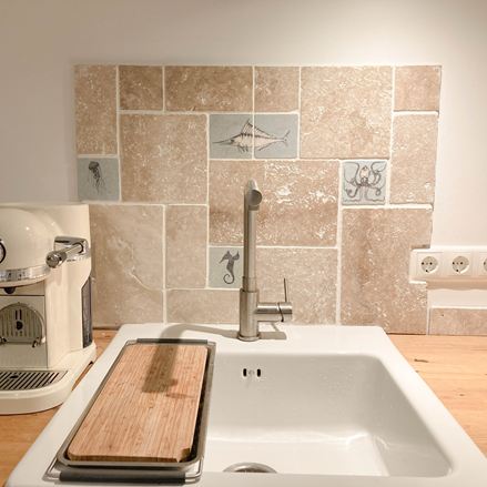 Crédence en carrelage en travertin au mur de la cuisine derrière l'évier
