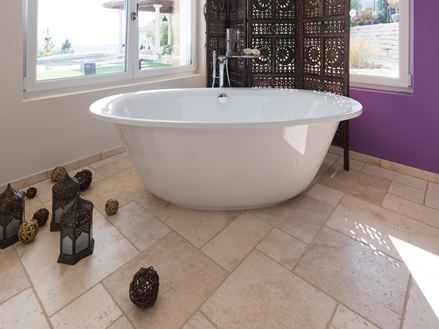 Une baignoire avec des accessoires orientaux sur le sol en travertin Light (tambouriné)