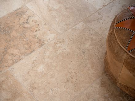 En détail : carrelage Rustic, en travertin tambouriné, à droite un pouf marocain