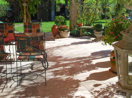 Le travertin Medium SELECT est en arrière plan des meubles de jardin, des plantes diverses et la pelouse