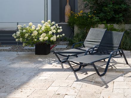 Terrasse en travertin Rustic avec deux chaises longues et un pot de fleurs