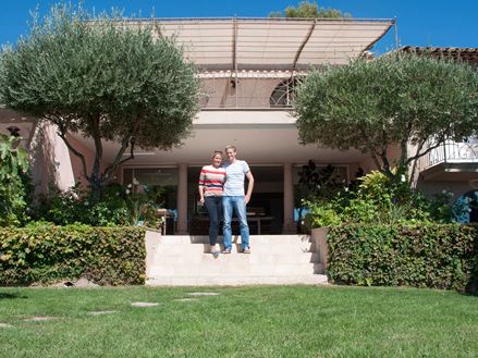 deux personnes sur les escaliers de la maison en premier plan le jardin et derrière une maison